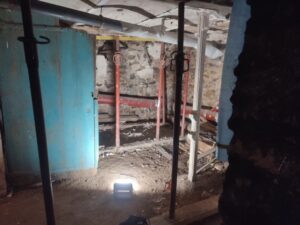 Photo prise pendans nos investigations dans le cadre d'un diagnostic structurel montrant des étais soutenant le plancher haut des caves avec un éclairage par projecteurs pour une meilleure visibilité.